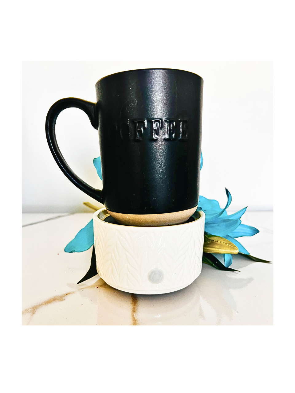 Black mug with 'OFFICE' text on a marble surface with a blue flower.